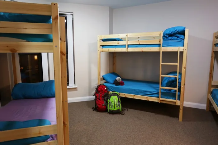 Wooden bunk beds made up with blue linen in one of our dorm rooms